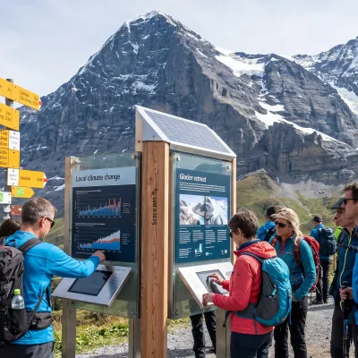 Wanderer lesen eine interaktive Informationstafel des Klimaguides auf der Kleinen Scheidegg mit der Eigernordwand im Hintergrund